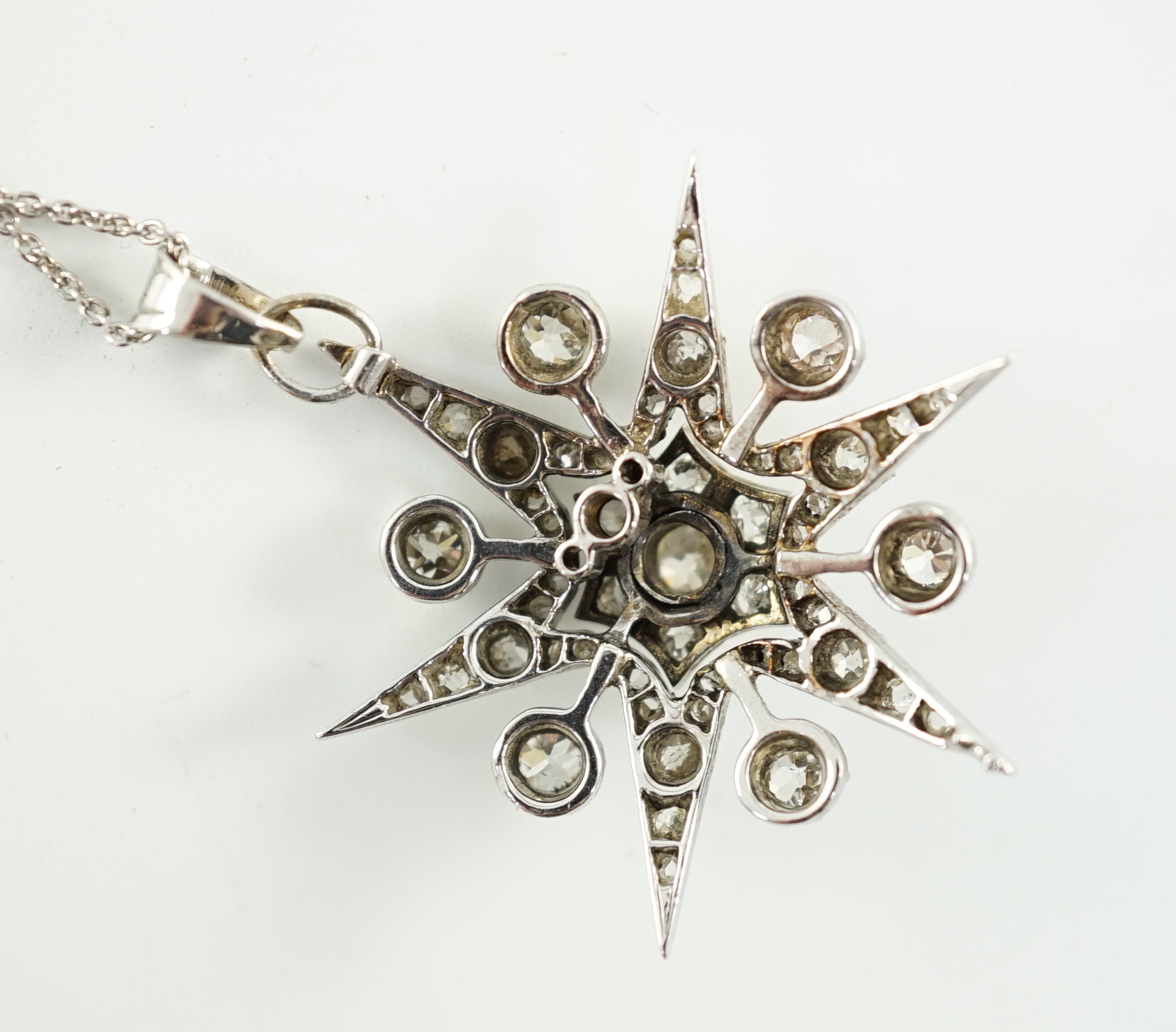 A Victorian white gold and diamond cluster set star burst pendant, on a later sterling chain